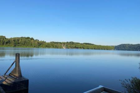 Blick auf den See in Heisingen mit grünem Ufer und klarem Himmel – Sinnbild für Natur und Klimaschutz.