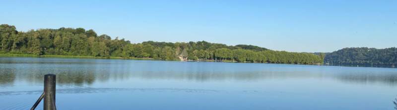 Blick auf den See in Heisingen mit grünem Ufer und klarem Himmel – Sinnbild für Natur und Klimaschutz.